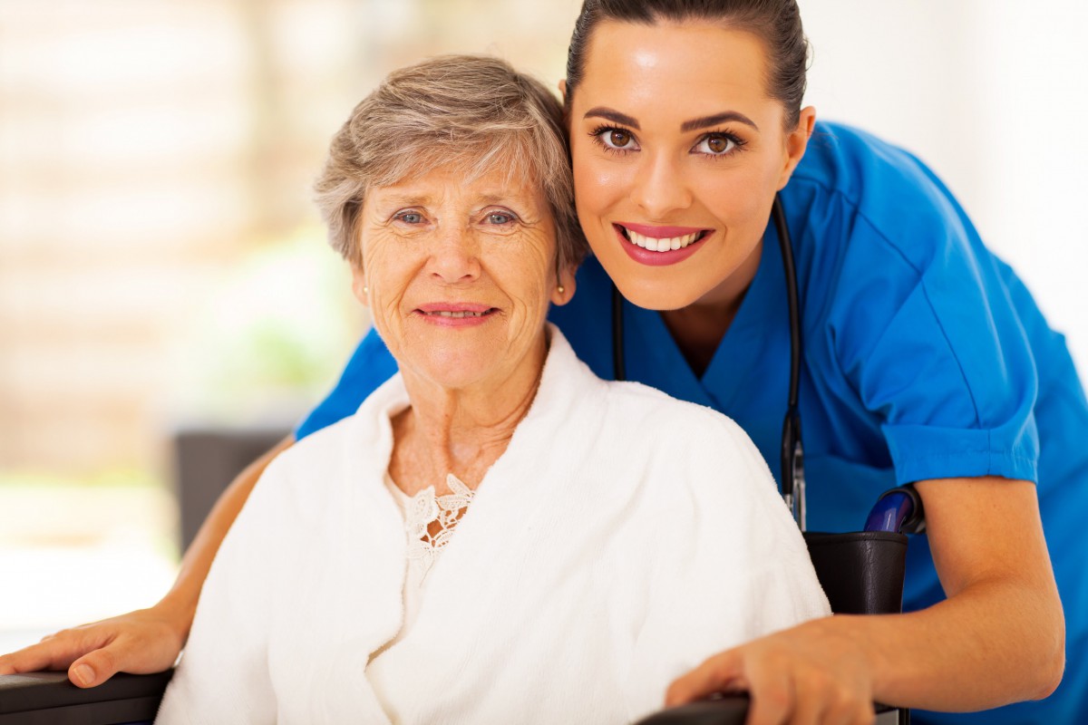 A caregiver and an elderly woman smiling together.