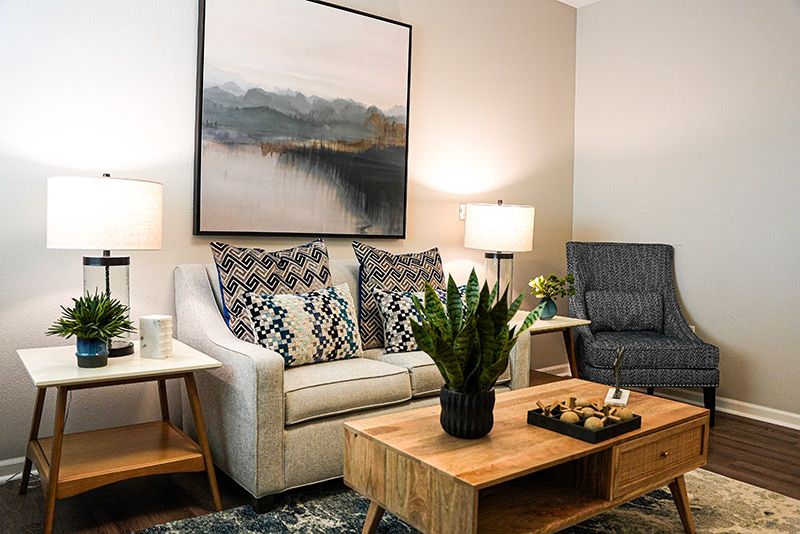 A modern living room featuring a comfortable sofa, a wooden coffee table with an indoor plant, lamps, and wall art.