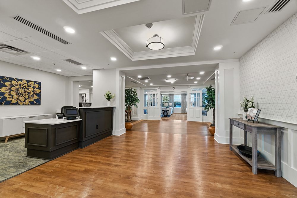 A modern and spacious office reception area with a wooden floor, reception desk, and decorative plants.