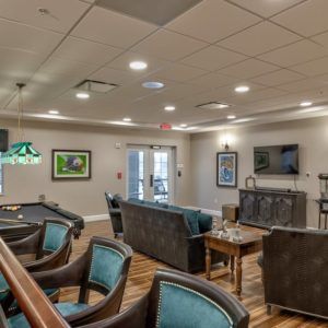A spacious lounge area featuring comfortable seating, a pool table, and a television.