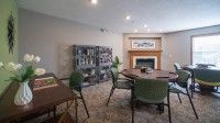 A cozy room with a dining table, chairs, bookshelf, and fireplace.