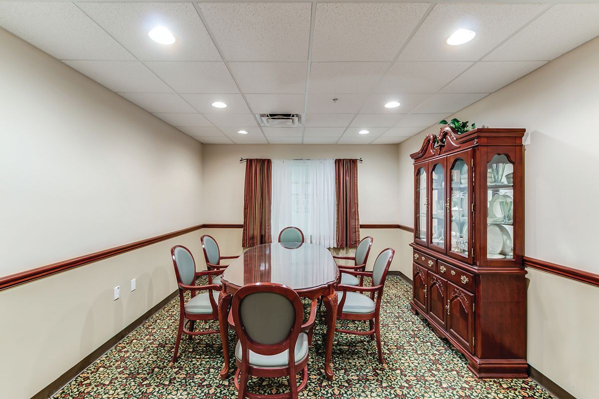 A small conference room with a round table and six chairs, featuring a wooden cabinet against the wall.