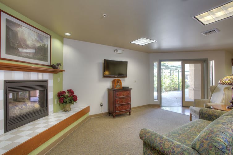 A cozy living room featuring a fireplace, wall-mounted television, and comfortable seating with ample natural light.