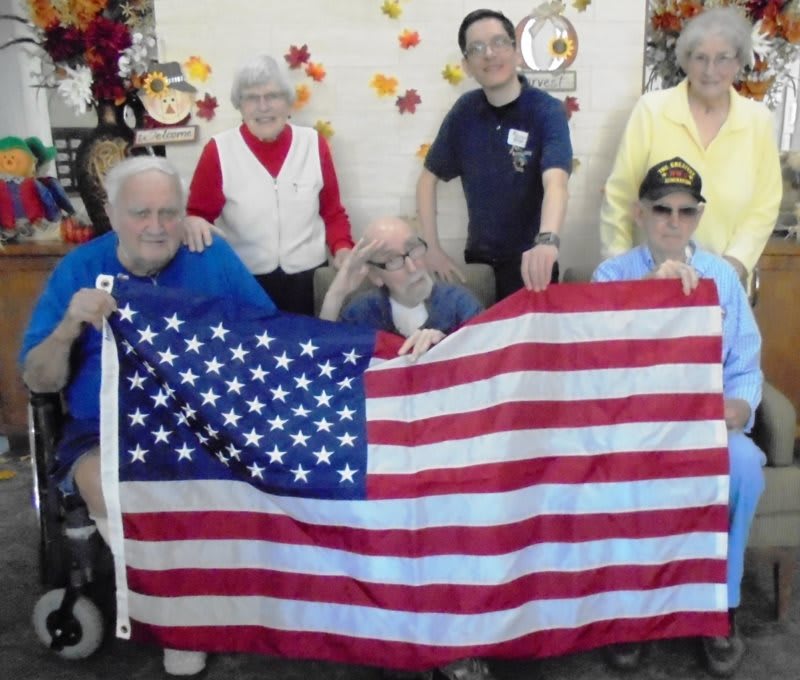 A group of people posing indoors with an American flag.