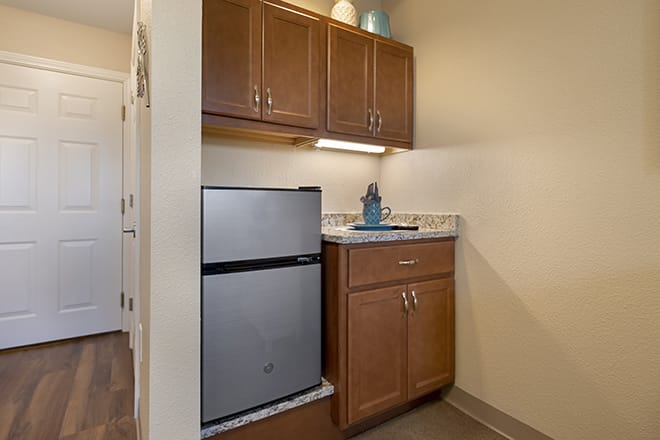 Compact kitchen space with a mini fridge and wooden cabinets.