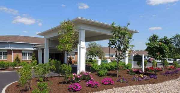 A landscaped garden with vibrant flowers and trees surrounding a white outdoor pavilion.
