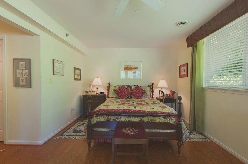 A cozy bedroom featuring a large bed with decorative pillows, bedside tables with lamps, and framed artwork on the walls.
