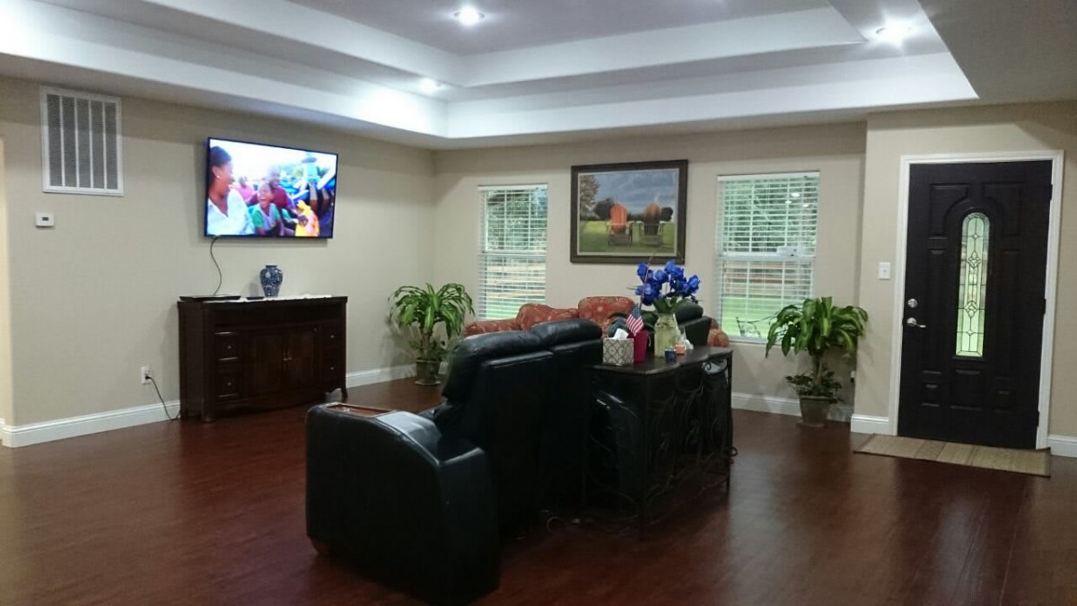 A cozy living room with comfortable seating, a television, and decorative plants.