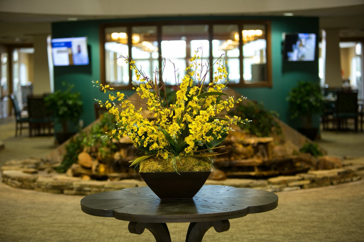 A vibrant yellow floral arrangement on a table in a lobby setting.