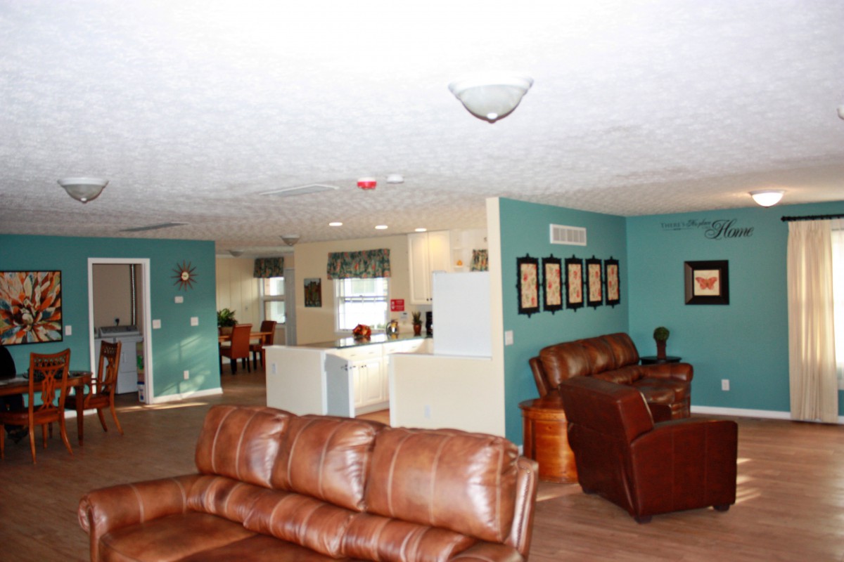 An open-concept living room with leather sofas and a view of the kitchen.