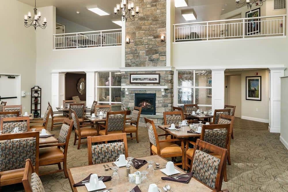 A modern dining area with stylish furniture, a stone fireplace, and a view of the upper level.