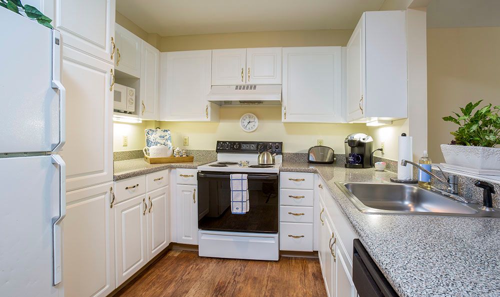 A modern kitchen with white cabinets, featuring a stove and various appliances.