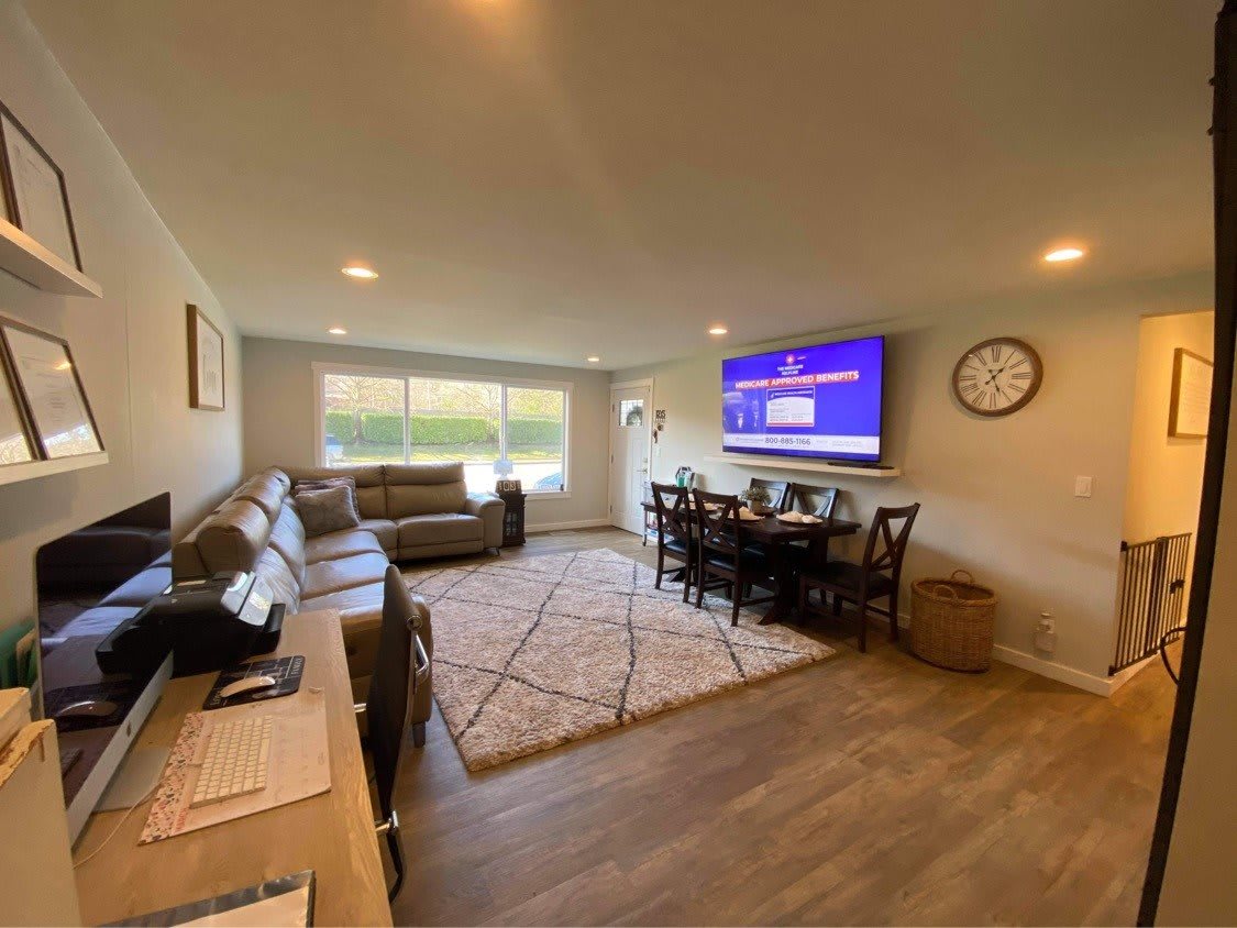 A cozy living room featuring comfortable sofas, a dining area, and a wall-mounted TV.