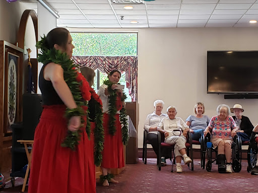 A vibrant hula dance performance taking place for an engaged elderly audience.