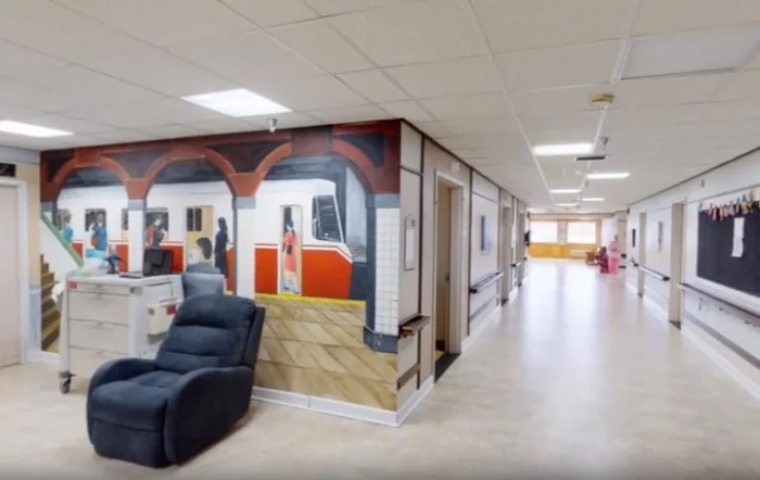 A hallway featuring a mural of a train scene with a comfortable recliner placed nearby.