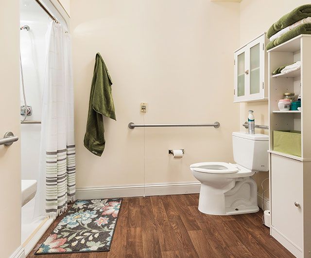 A clean, organized bathroom with a shower, toilet, and wood flooring.