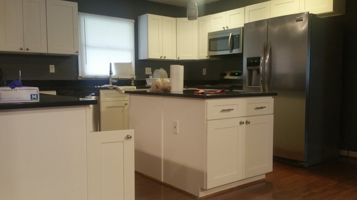 A modern kitchen with white cabinets, a central island, and stainless steel appliances.