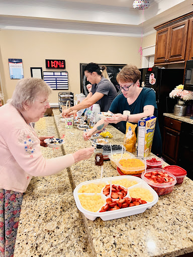 Volunteers preparing snacks in a welcoming kitchen environment for residents.