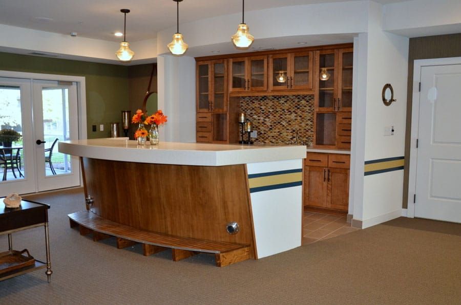 A modern kitchen interior featuring a sleek wooden counter and cabinetry, with pendant lighting and decorative elements.