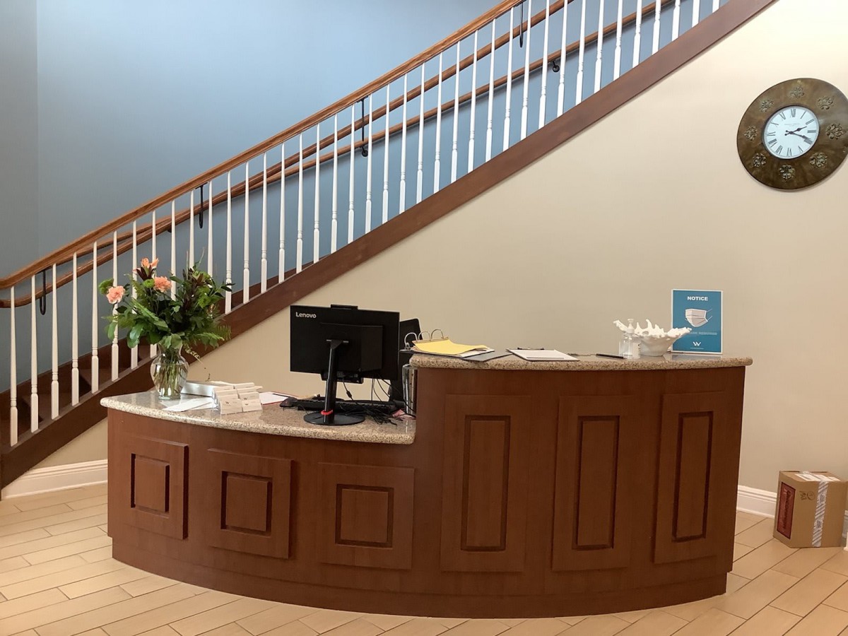 A reception desk in front of a staircase in an office setting.