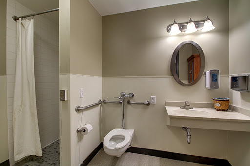 A modern accessible bathroom featuring a toilet, sink, and grab bars.