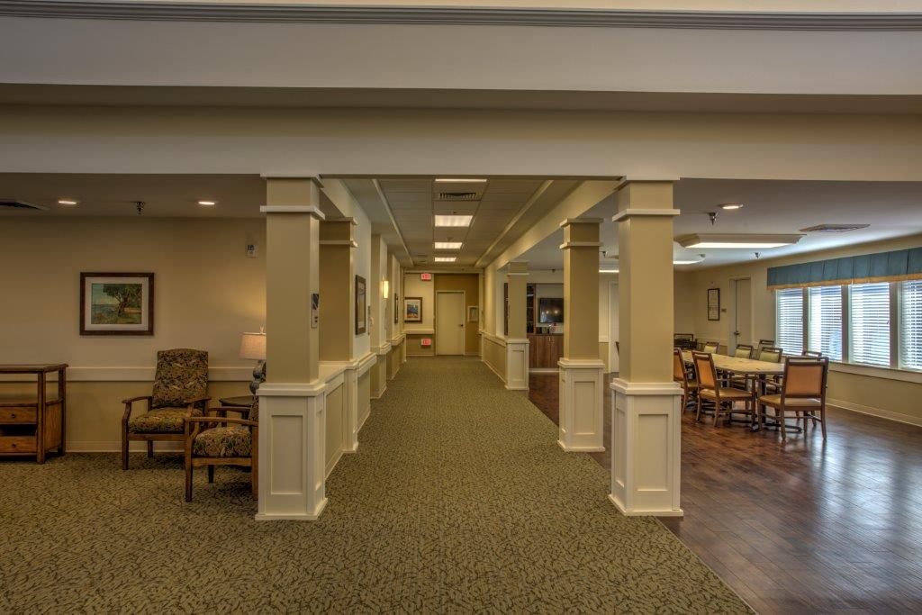 A well-lit interior hallway with columns and a seating area on the left.
