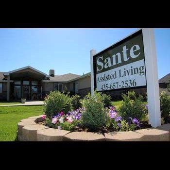 A well-maintained assisted living facility with a prominent sign and landscaped garden.