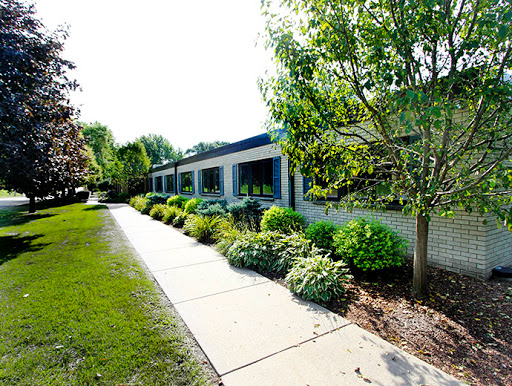 A serene view of a building surrounded by lush greenery and a well-maintained pathway.