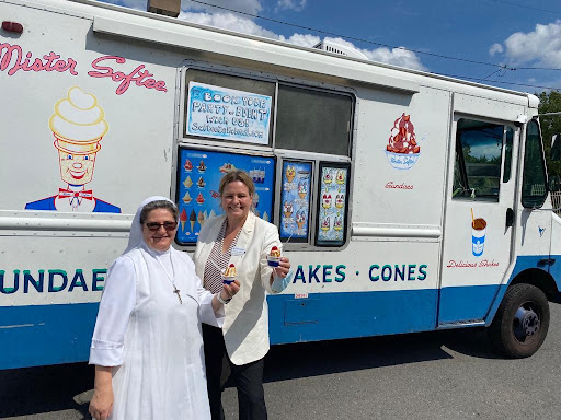 Two women enjoying ice cream outside an ice cream truck on a sunny day.