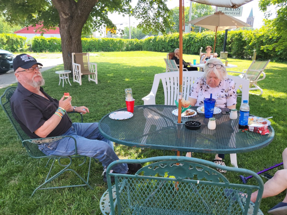 Two people enjoying a picnic in a garden setting.