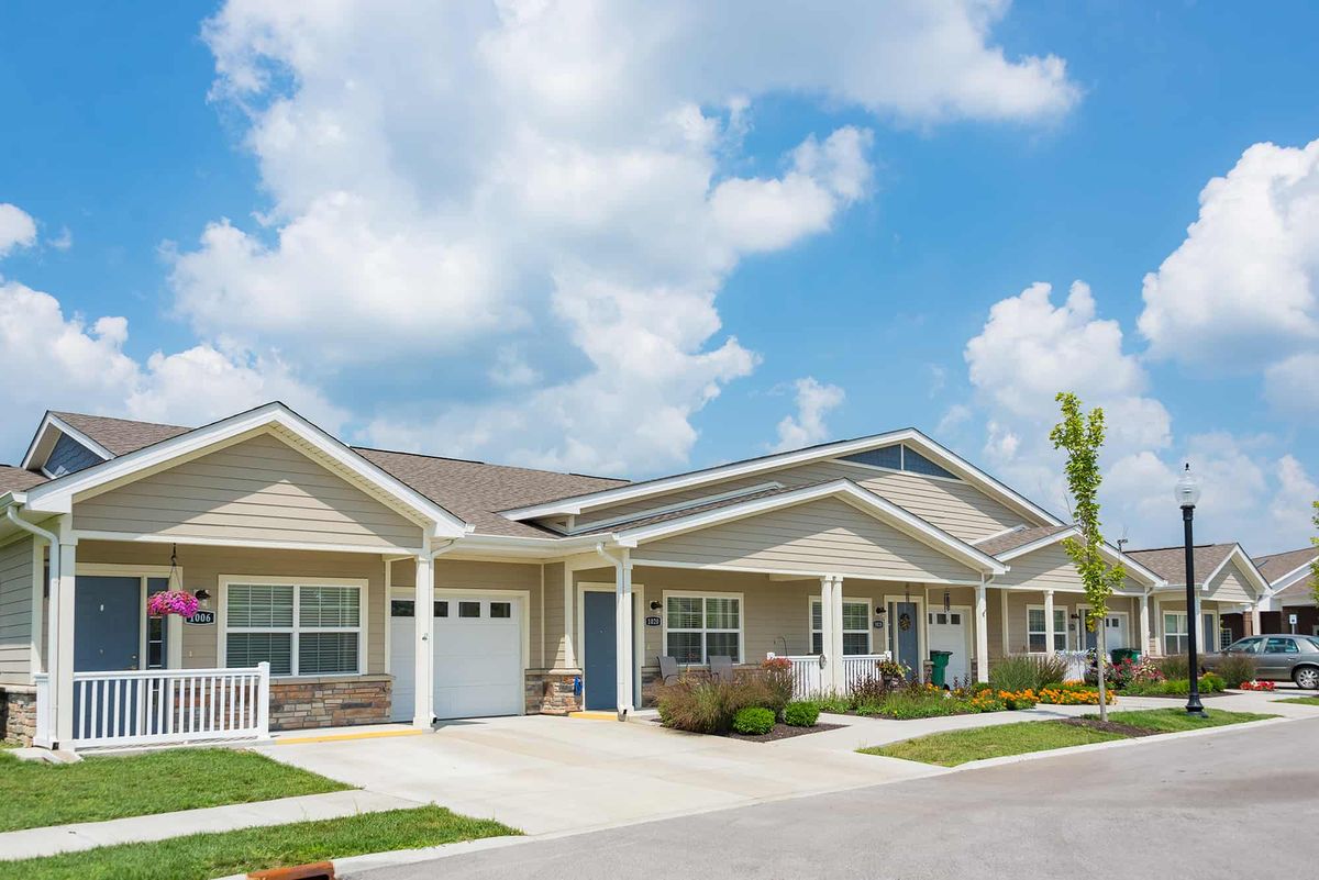 A row of modern suburban homes under a blue sky with scattered clouds.