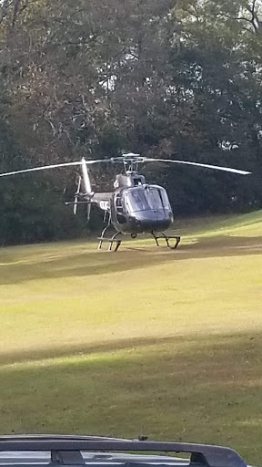 A helicopter landing on a grassy field.