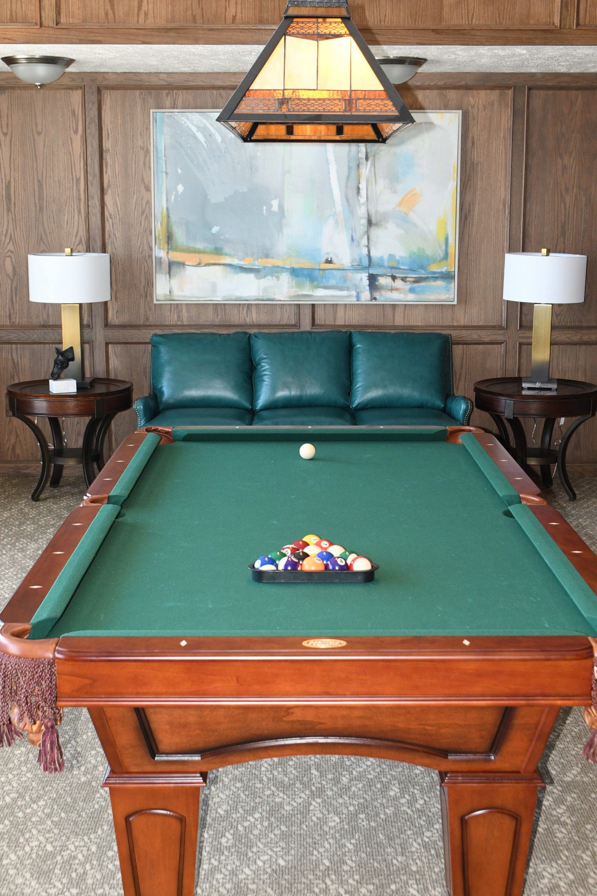 A stylish room featuring a pool table, sofa, and decorative lamps.