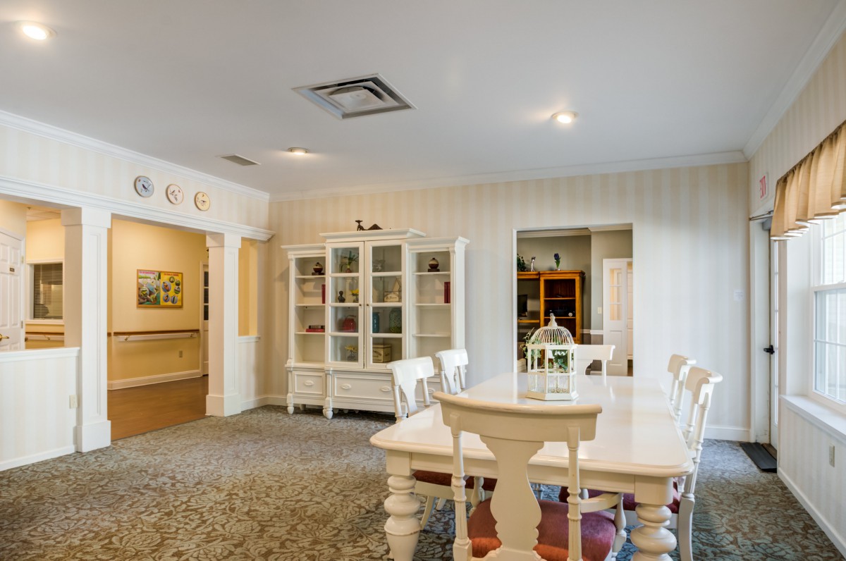 A cozy dining room featuring a large table, chairs, and a display cabinet in a well-lit interior.