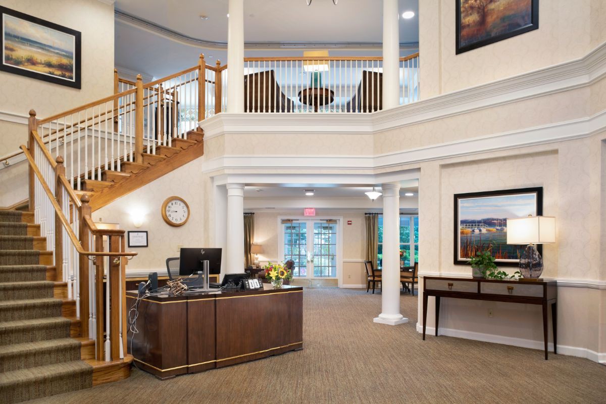 The image shows a spacious lobby area with a reception desk, staircase, and elegant decor.