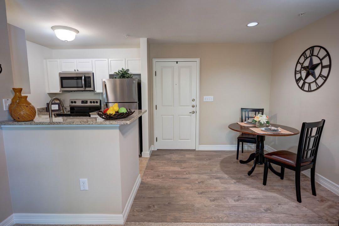 A modern apartment interior featuring an open-concept kitchen and dining area with wood flooring.