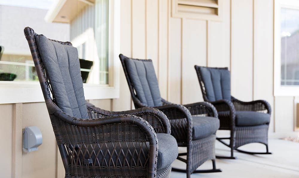 A row of wicker chairs on a sunny porch, perfect for relaxation.