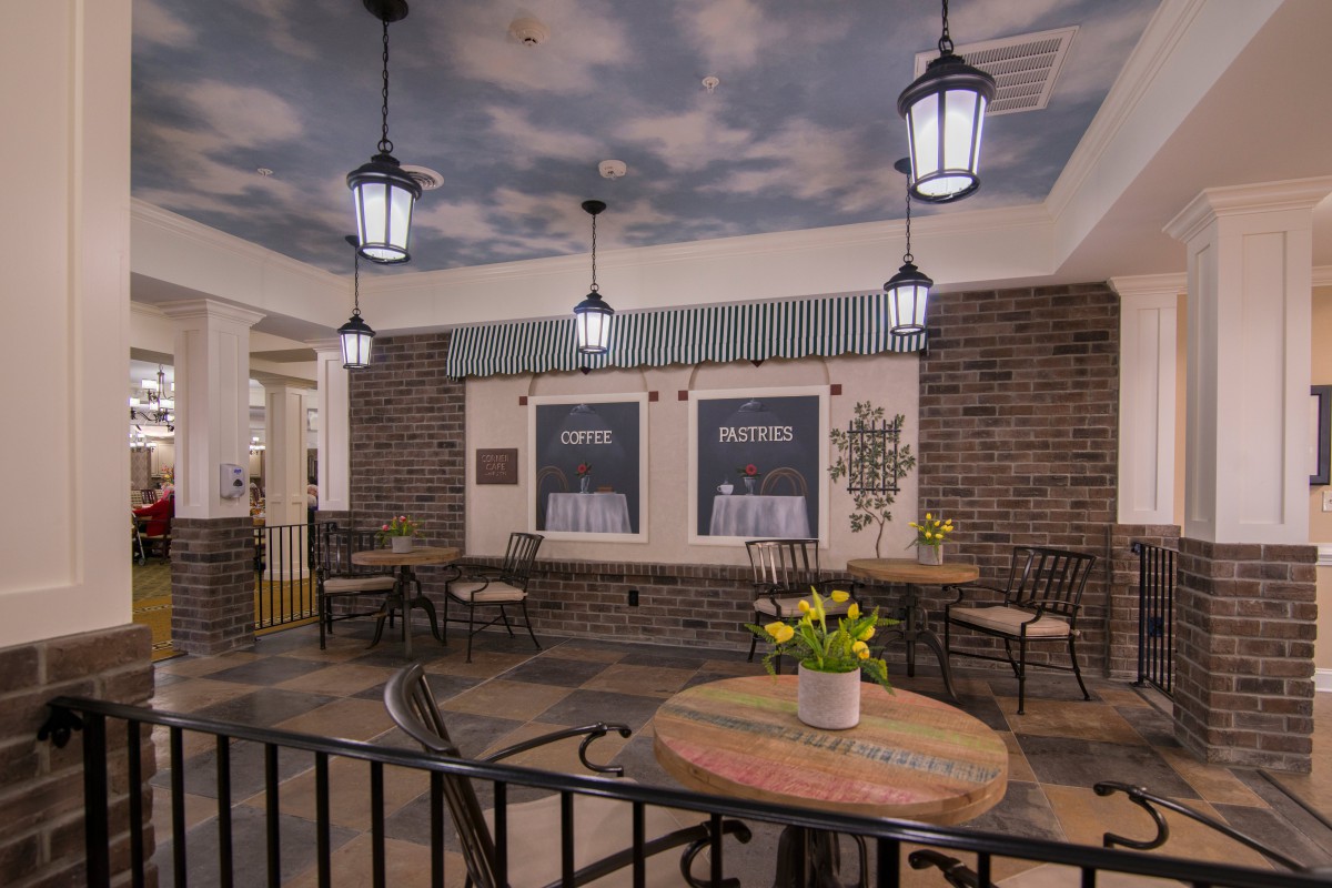 A cozy indoor cafe with brick walls, ceiling murals, and elegant lantern lighting.