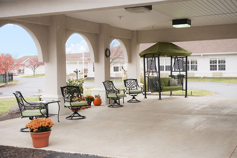 A cozy outdoor patio area with a gazebo, featuring chairs and tables, surrounded by potted plants.