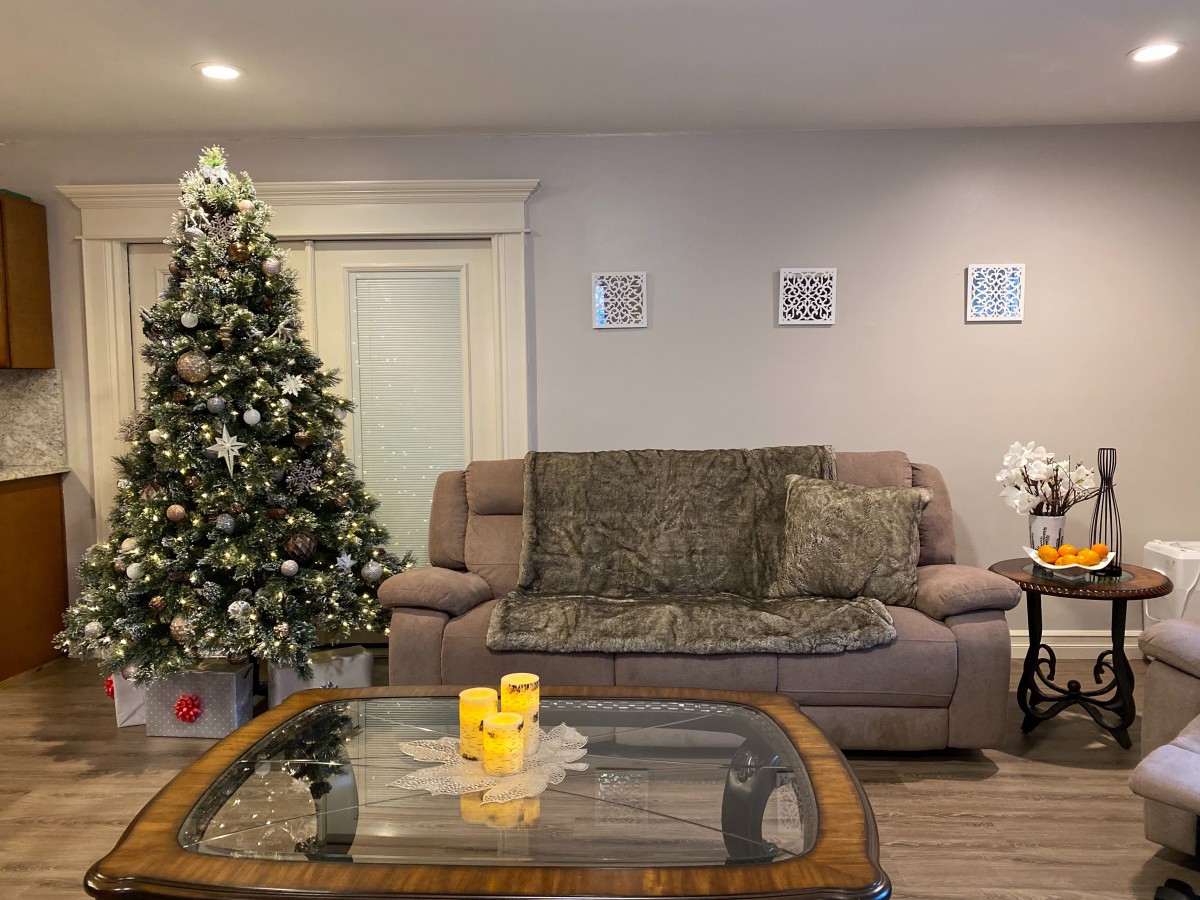 A cozy living room with a decorated Christmas tree and a comfortable sofa.