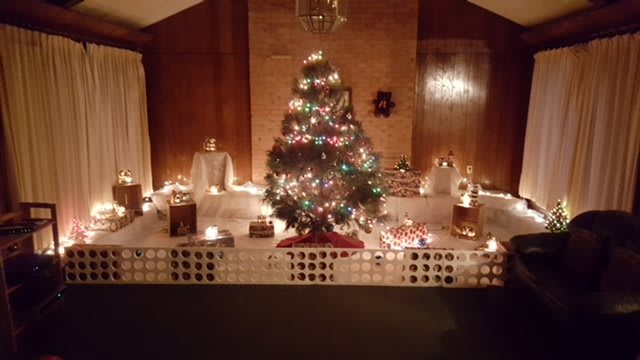 A warmly lit Christmas tree surrounded by festive decorations and lights.