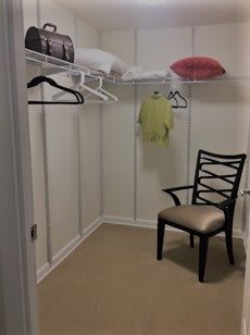 An empty walk-in closet with a chair and a few items on the shelves.