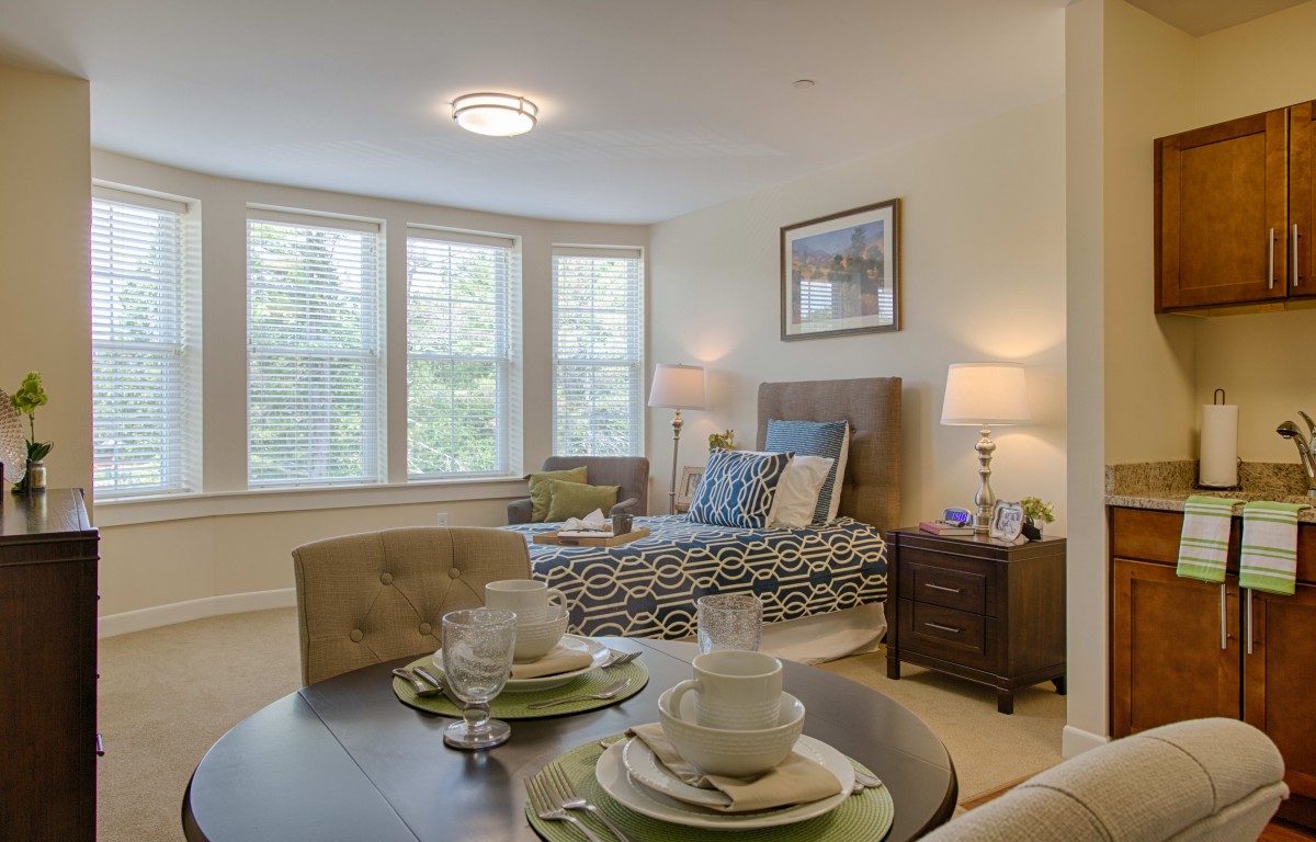 A cozy bedroom with a bed, nightstands, and a small dining area by the window.