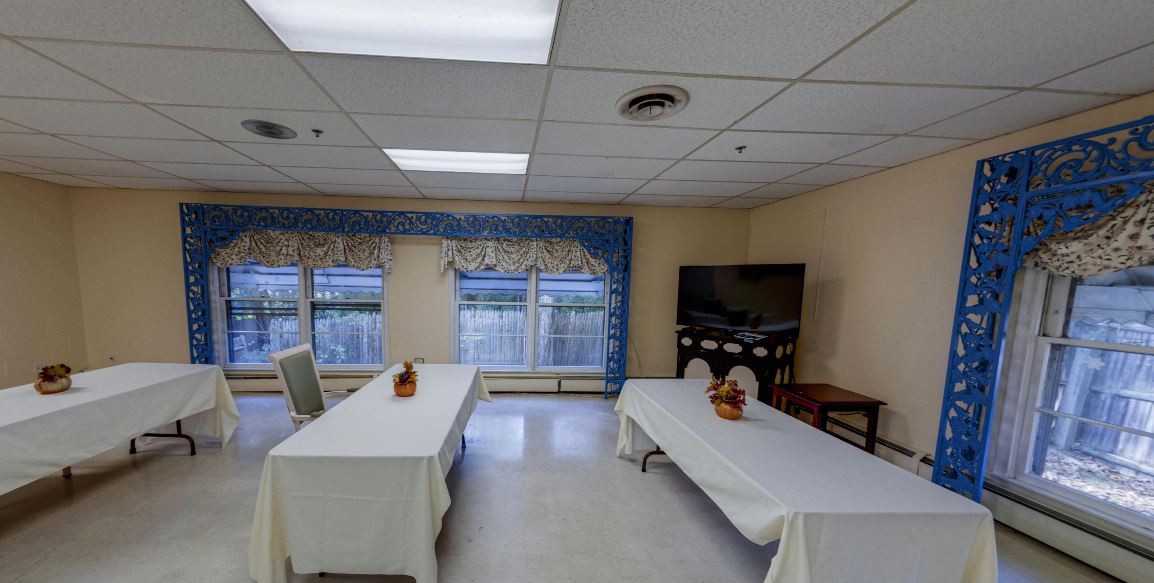 A well-lit meeting room with tables and a television arranged for a gathering.