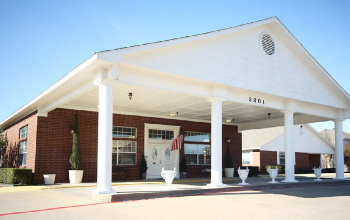 A building entrance with large white columns and a covered driveway.