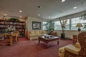 A cozy living room with a sofa, coffee table, bookshelf, and decorative elements.
