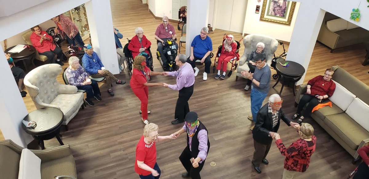 A lively gathering of elderly people dancing and enjoying a community event indoors.