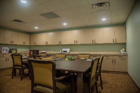 A conference room with a large table surrounded by chairs and cabinets lining the walls.