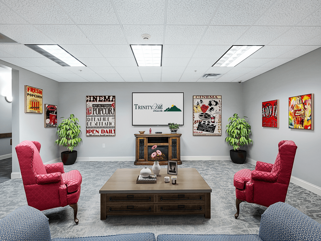 A modern office seating area with red chairs, artwork on the walls, and decorative plants.