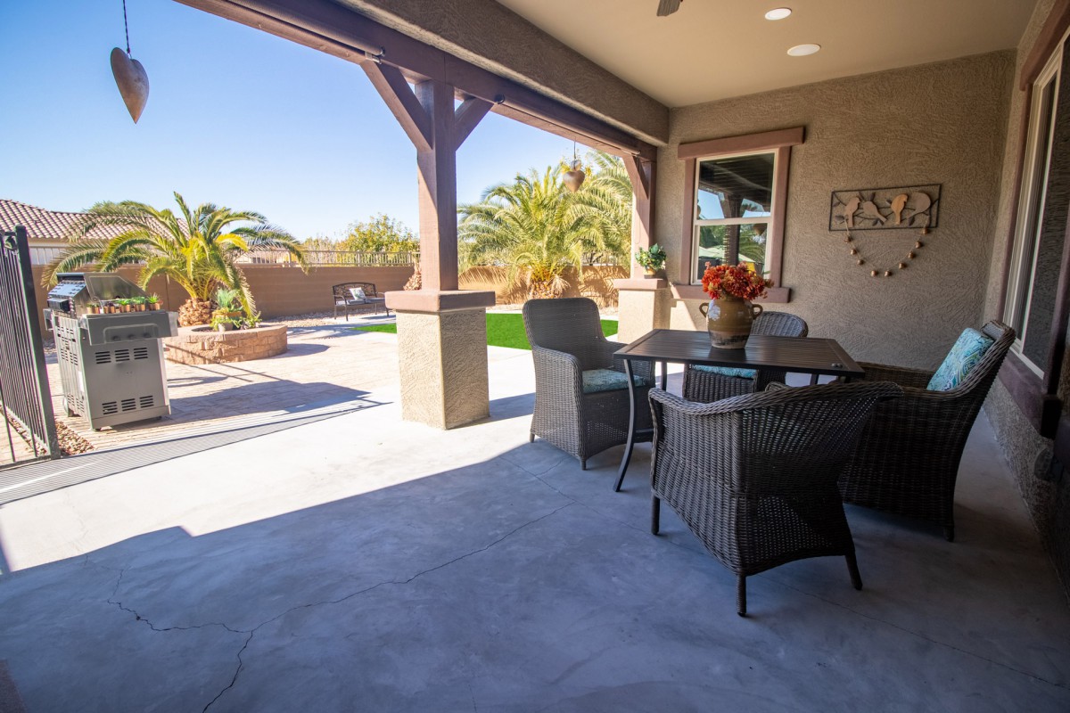 A sunny patio with outdoor furniture and a view of the backyard with palm trees.